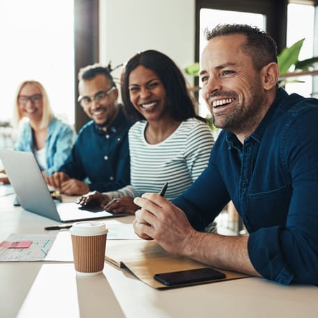 Diverse office colleagues laughing together during a meeting